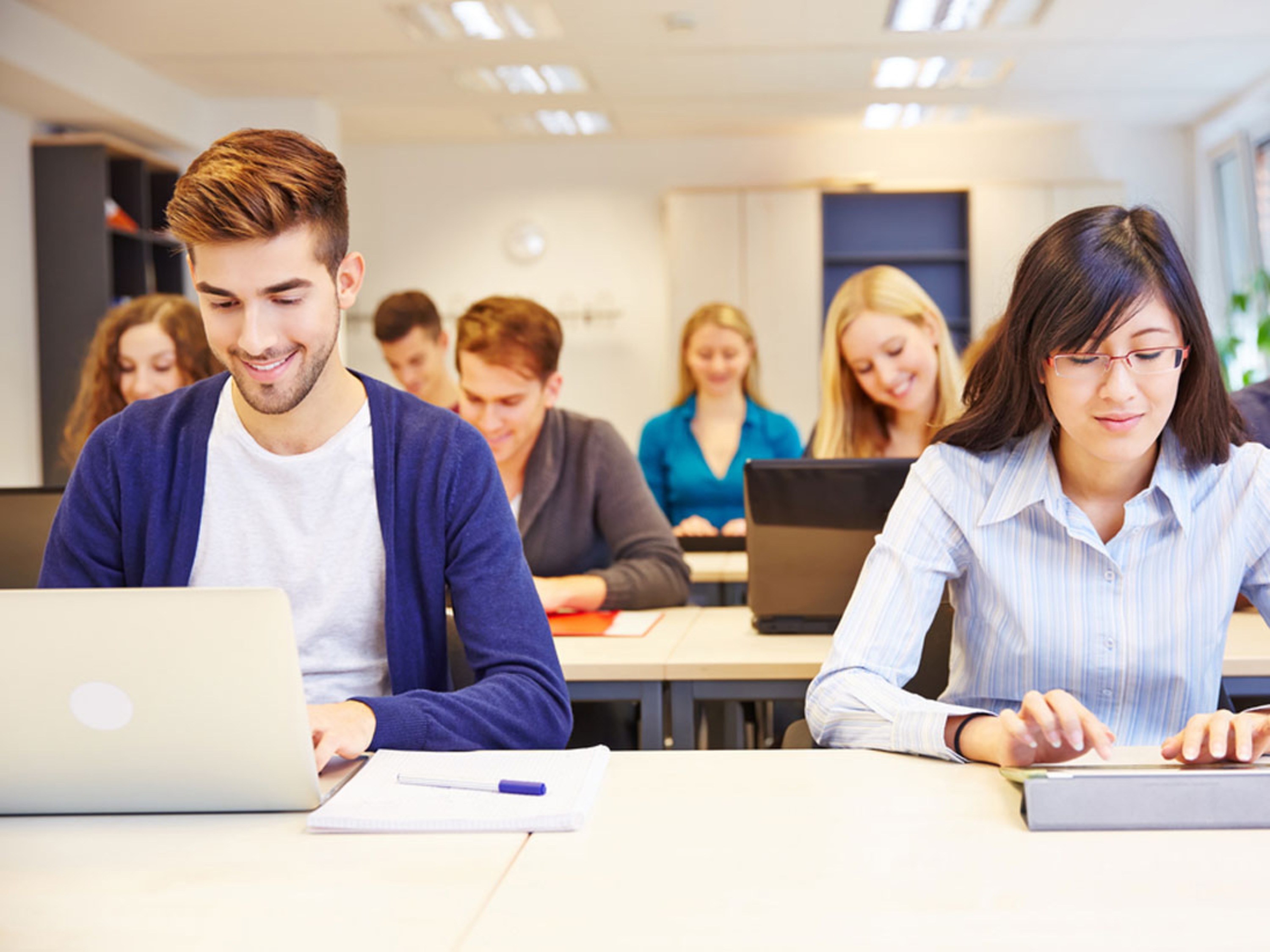 matricula dois jovens de ambos os sexos com notebook na sala de aula aparentemente de uma faculdade